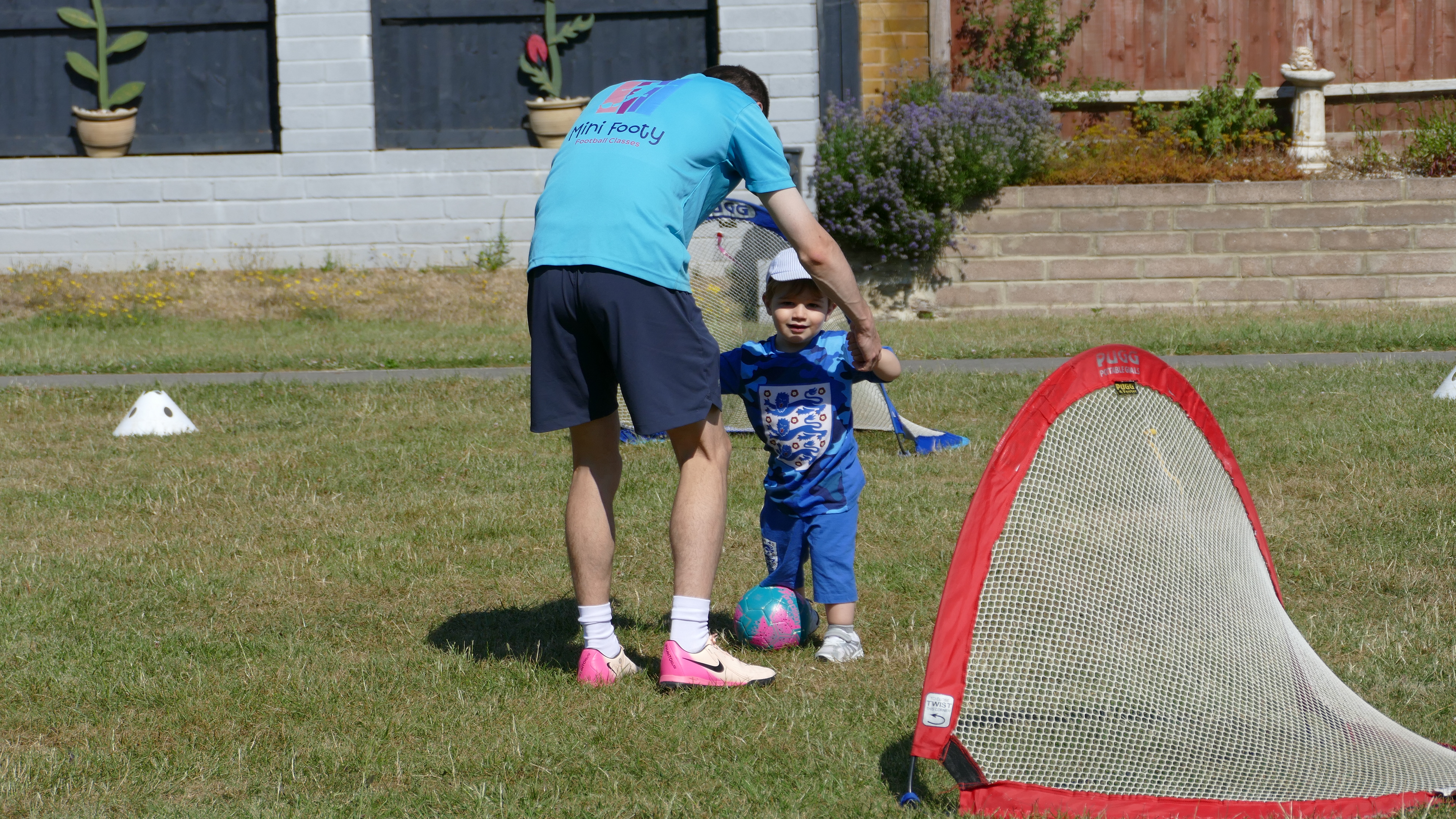 An adult helping a young child with a football activity at Mini Footy
